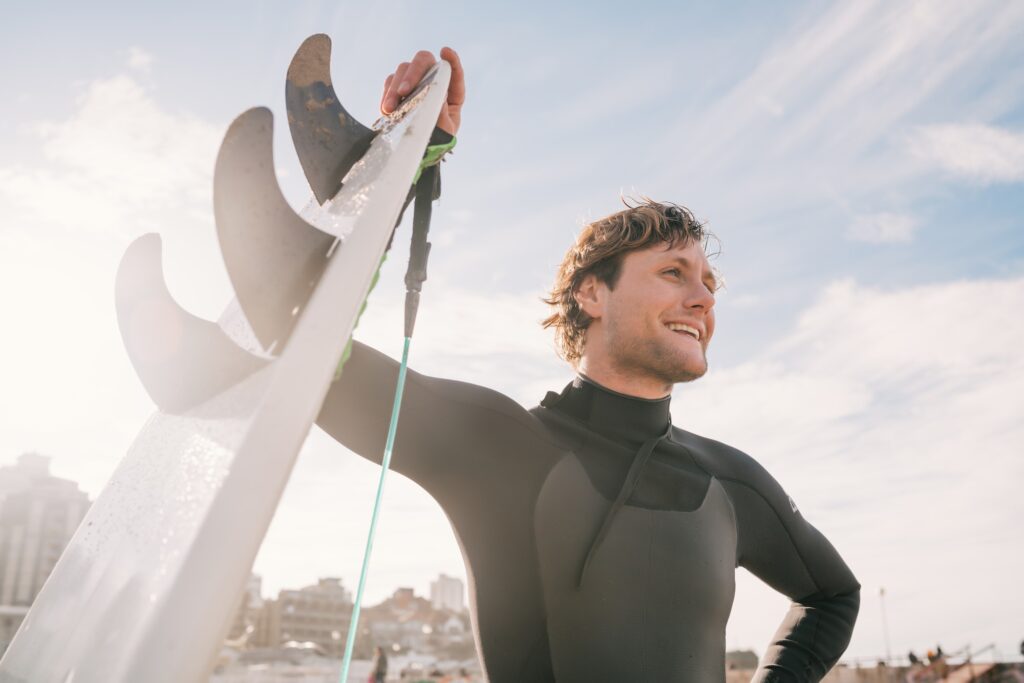 Surfer standing at the beach with surfboard.